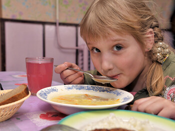 Ein Bub löffelt Suppe.